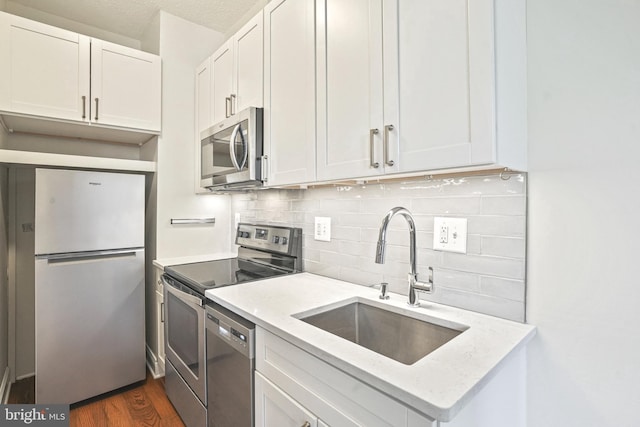 kitchen featuring appliances with stainless steel finishes, sink, white cabinetry, and light stone counters