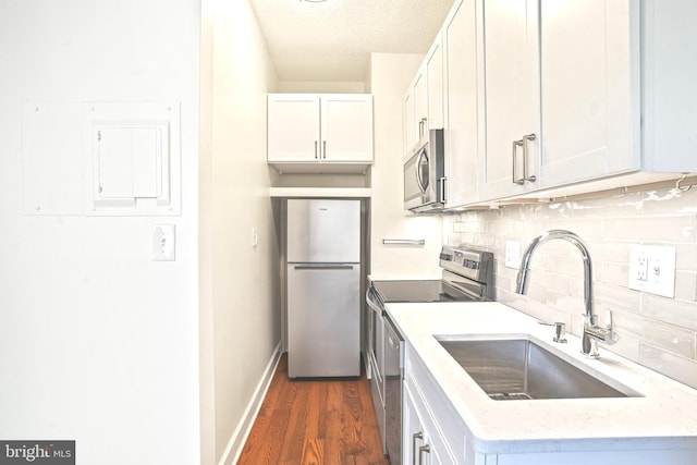 kitchen featuring appliances with stainless steel finishes, tasteful backsplash, dark wood-type flooring, sink, and white cabinetry