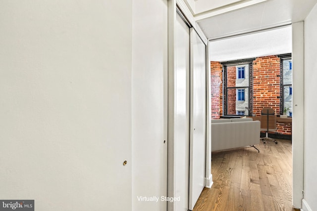 hall featuring light hardwood / wood-style flooring and brick wall