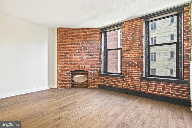 unfurnished living room with light wood-type flooring and a textured ceiling