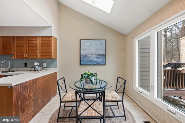 kitchen with light tile patterned floors, lofted ceiling with skylight, and sink