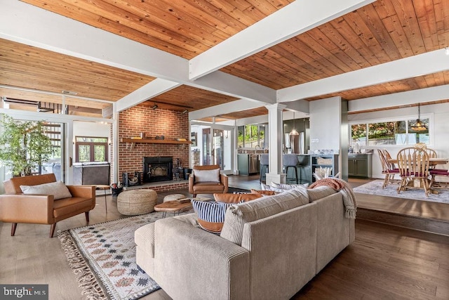 living room with a brick fireplace, plenty of natural light, beam ceiling, and wood ceiling