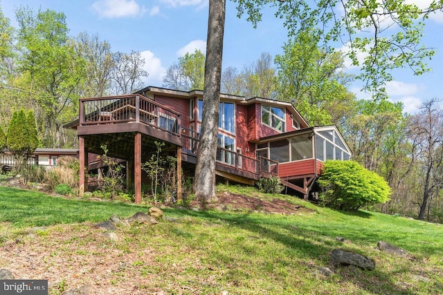 back of house with a deck, a yard, and a sunroom