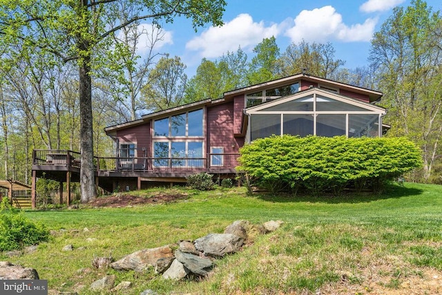 back of house featuring a deck, a yard, and a sunroom