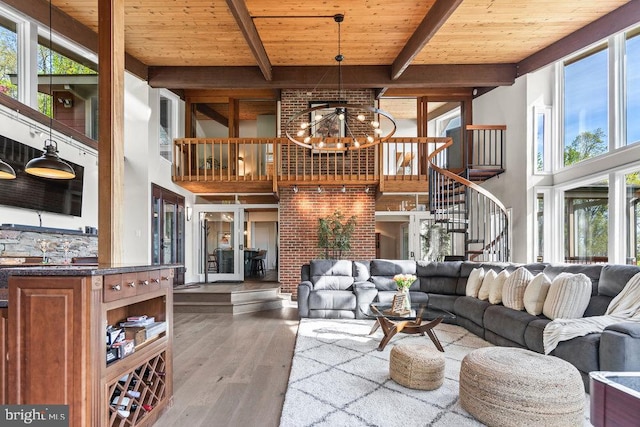 living room featuring wood-type flooring, beamed ceiling, a high ceiling, and wooden ceiling