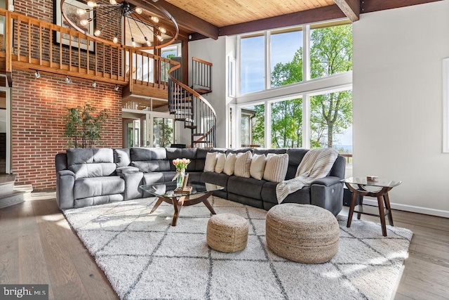 living room with an inviting chandelier, wooden ceiling, a towering ceiling, wood-type flooring, and beam ceiling