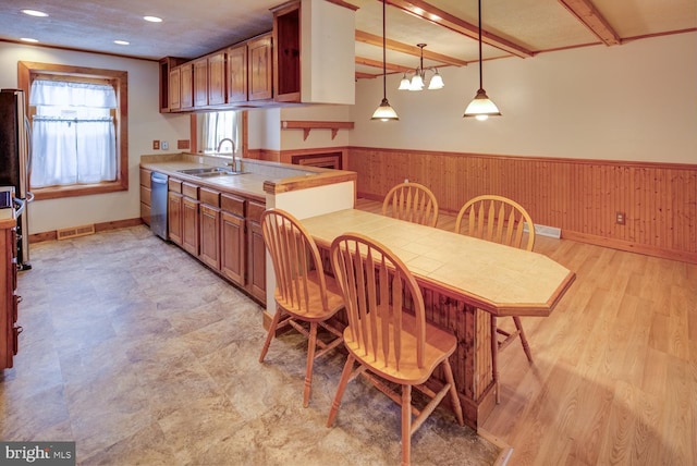 kitchen featuring kitchen peninsula, pendant lighting, appliances with stainless steel finishes, sink, and beamed ceiling