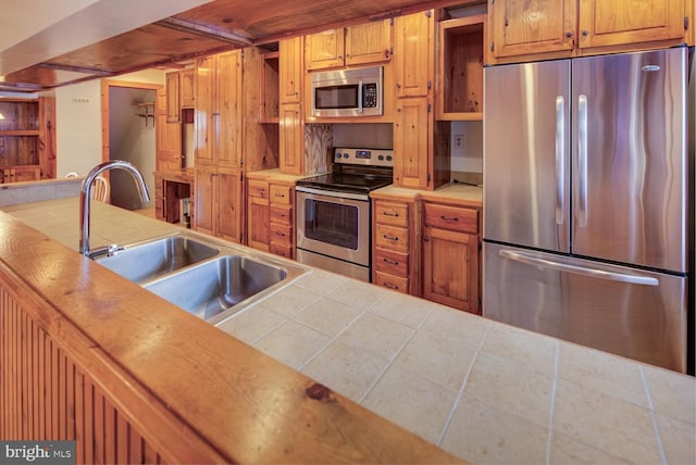 kitchen with sink, tile countertops, and appliances with stainless steel finishes