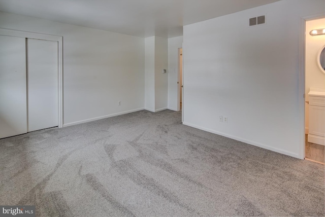 unfurnished bedroom featuring a closet, ensuite bath, and carpet