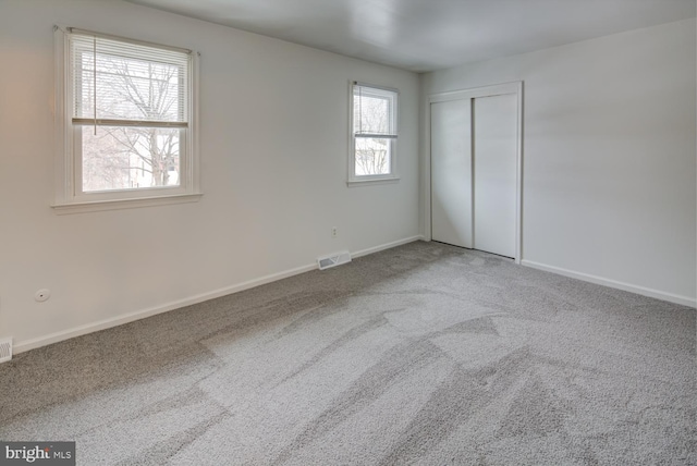 unfurnished bedroom featuring multiple windows, carpet floors, and a closet