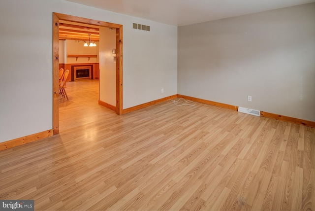 unfurnished room featuring an inviting chandelier and light hardwood / wood-style flooring