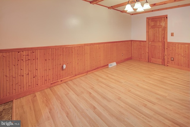 spare room with light wood-type flooring and a chandelier