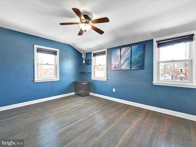 empty room with vaulted ceiling, a wealth of natural light, ceiling fan, and dark hardwood / wood-style flooring