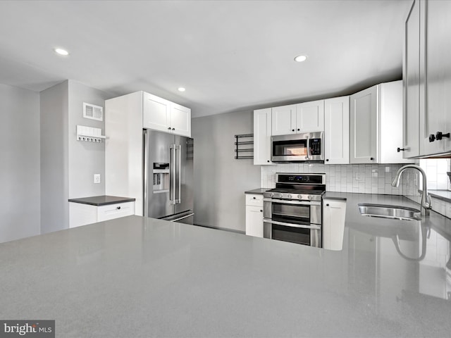 kitchen featuring sink, backsplash, white cabinets, and appliances with stainless steel finishes