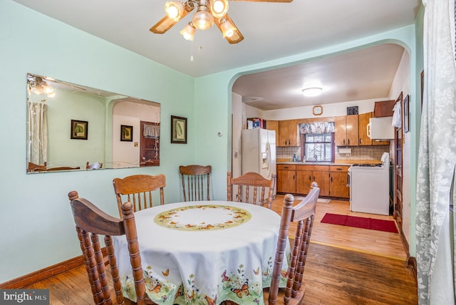 dining room featuring ceiling fan, sink, and light hardwood / wood-style flooring