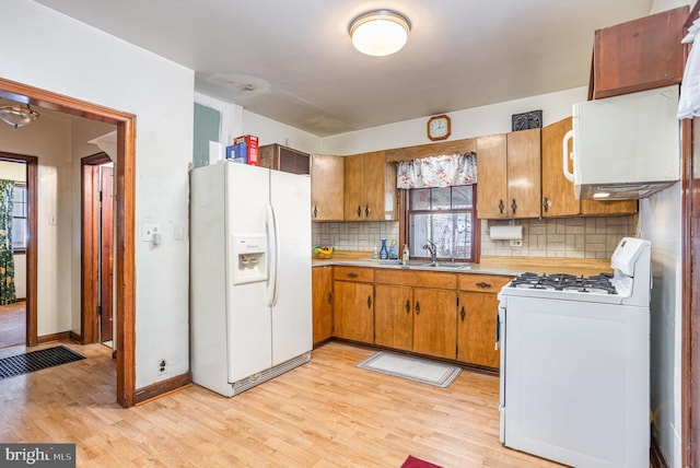 kitchen featuring sink, backsplash, white appliances, and light hardwood / wood-style floors