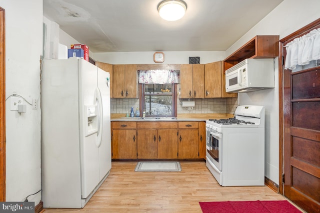 kitchen featuring tasteful backsplash, white appliances, sink, and light wood-type flooring