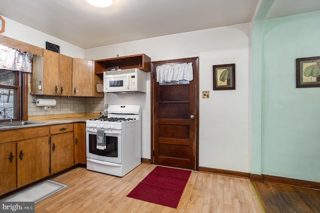 kitchen with sink, decorative backsplash, white appliances, and light hardwood / wood-style flooring