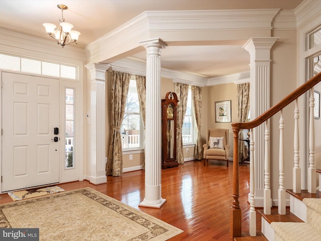 entrance foyer featuring ornate columns, crown molding, hardwood / wood-style flooring, and a chandelier