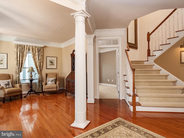 interior space featuring ornate columns, crown molding, and hardwood / wood-style flooring