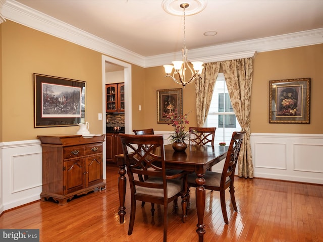 dining space with an inviting chandelier, ornamental molding, and light hardwood / wood-style floors