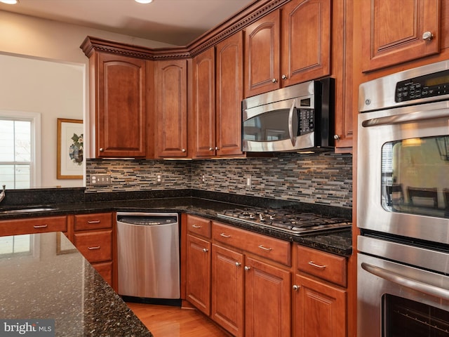 kitchen featuring tasteful backsplash, stainless steel appliances, sink, and dark stone counters