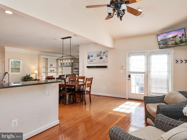 living room featuring vaulted ceiling, sink, ceiling fan with notable chandelier, and light hardwood / wood-style flooring