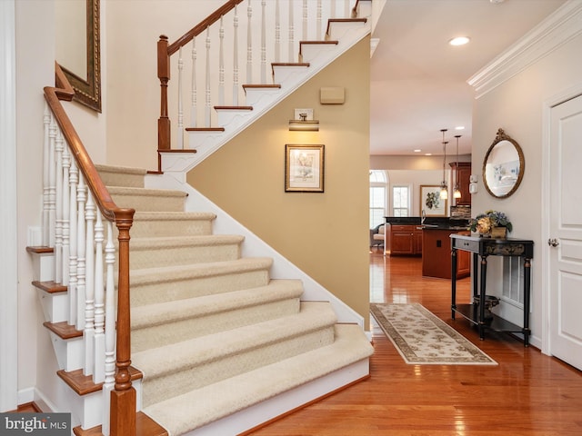 stairs featuring crown molding and wood-type flooring