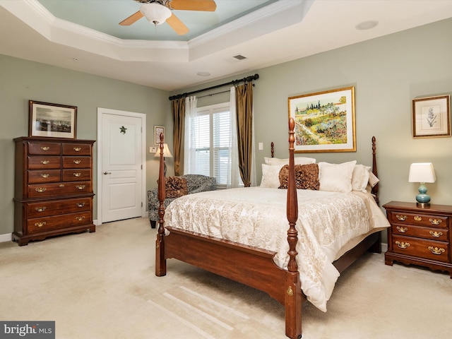 carpeted bedroom featuring ceiling fan, ornamental molding, and a tray ceiling