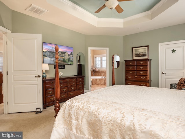 carpeted bedroom featuring ceiling fan, ensuite bath, ornamental molding, and a tray ceiling