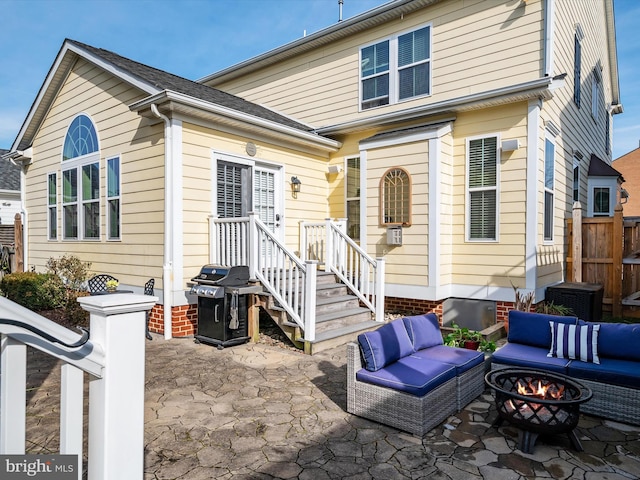 rear view of house with a patio and an outdoor living space with a fire pit