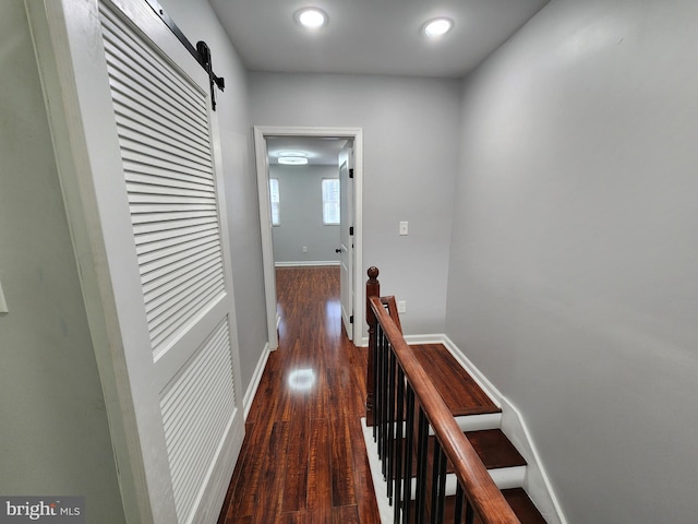 hallway with a barn door and dark hardwood / wood-style floors