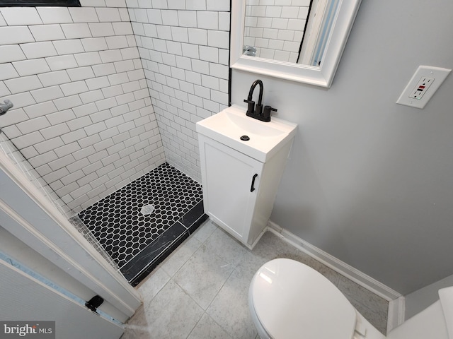 bathroom with toilet, vanity, and a tile shower