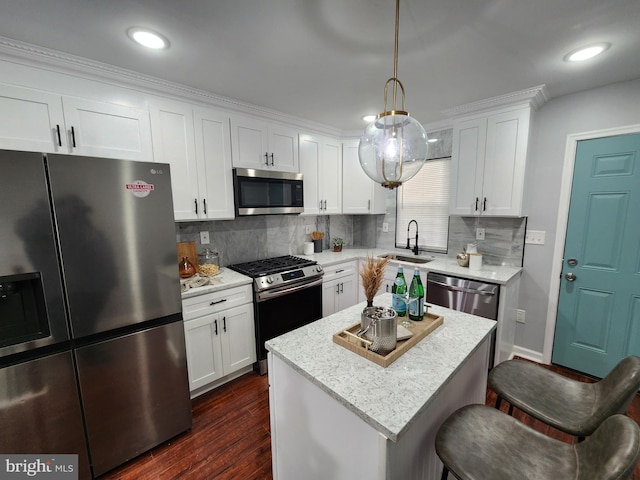 kitchen with stainless steel appliances, backsplash, white cabinetry, and hanging light fixtures