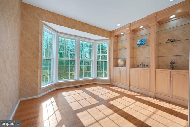 interior space with light wood-type flooring, wallpapered walls, plenty of natural light, and baseboards