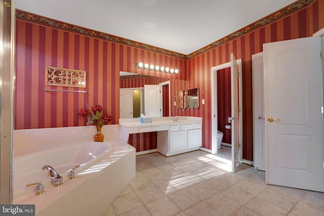 bathroom with baseboards, a garden tub, vanity, and wallpapered walls