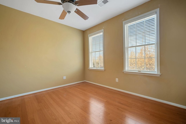 spare room with visible vents, ceiling fan, baseboards, and wood finished floors