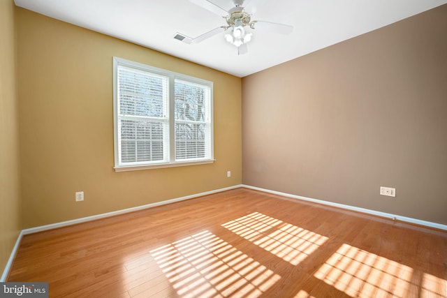 spare room featuring ceiling fan, light wood-type flooring, visible vents, and baseboards