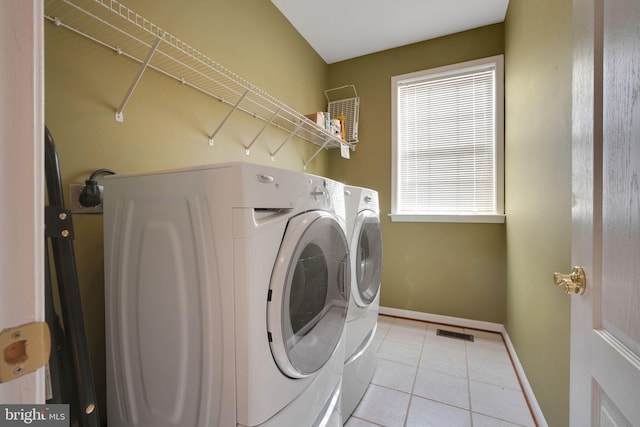 clothes washing area with light tile patterned floors, visible vents, separate washer and dryer, laundry area, and baseboards