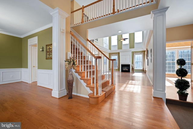 foyer entrance featuring a glass covered fireplace, wood finished floors, and ornate columns