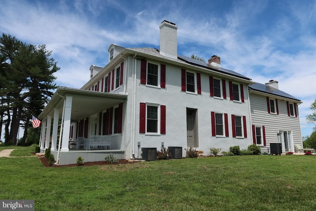 5961 Limestone Rd, Hockessin, DE 19707 - rear view of property featuring a chimney, roof mounted solar panels, a lawn, and central AC