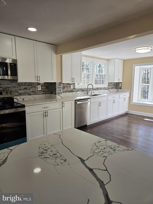 kitchen featuring tasteful backsplash, sink, white cabinets, light stone counters, and stainless steel appliances