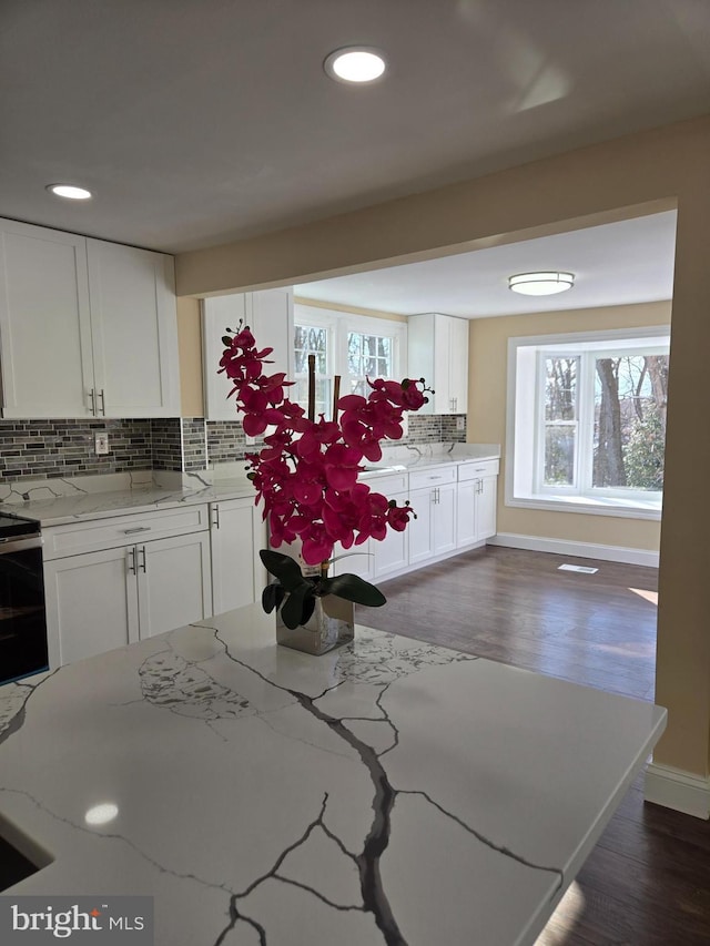 kitchen with white cabinetry, a wealth of natural light, light stone counters, and decorative backsplash