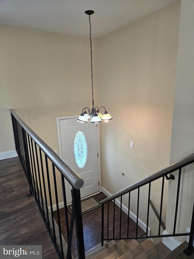 stairs featuring wood-type flooring and a chandelier