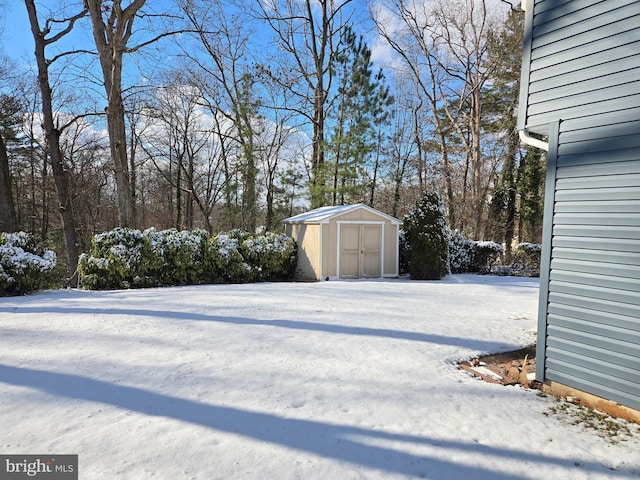 snowy yard with a storage shed