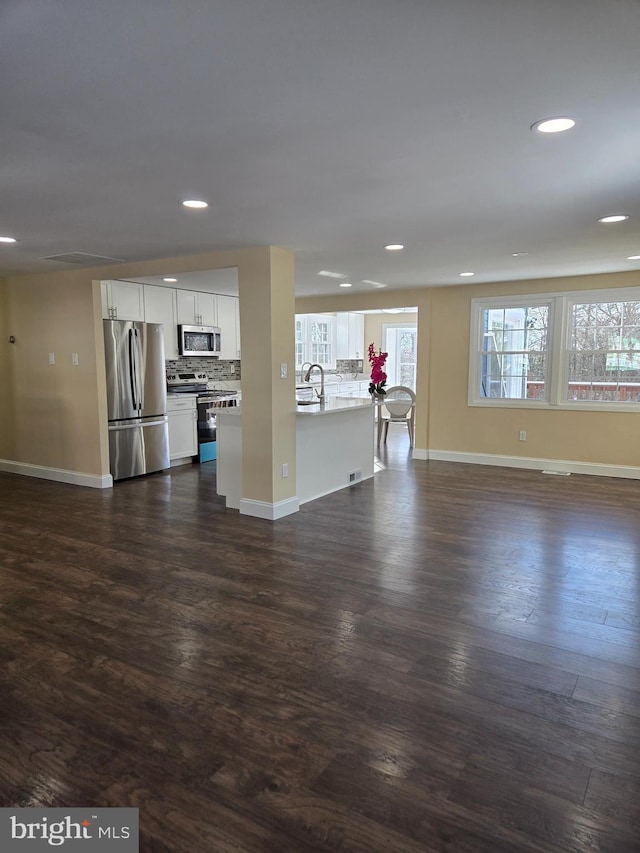 unfurnished living room featuring dark wood-type flooring, a healthy amount of sunlight, and sink