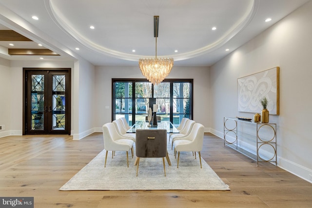 dining area featuring french doors, a raised ceiling, baseboards, and wood finished floors