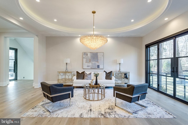 living area featuring an inviting chandelier, a tray ceiling, recessed lighting, and wood finished floors