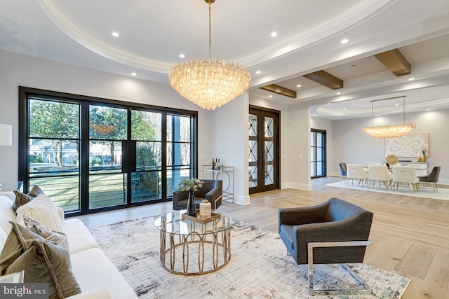 living room with a notable chandelier, a raised ceiling, baseboards, and wood finished floors