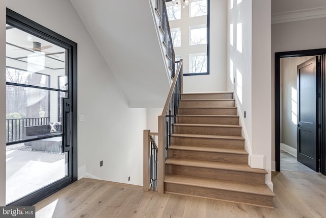 stairs with ornamental molding, baseboards, and wood finished floors